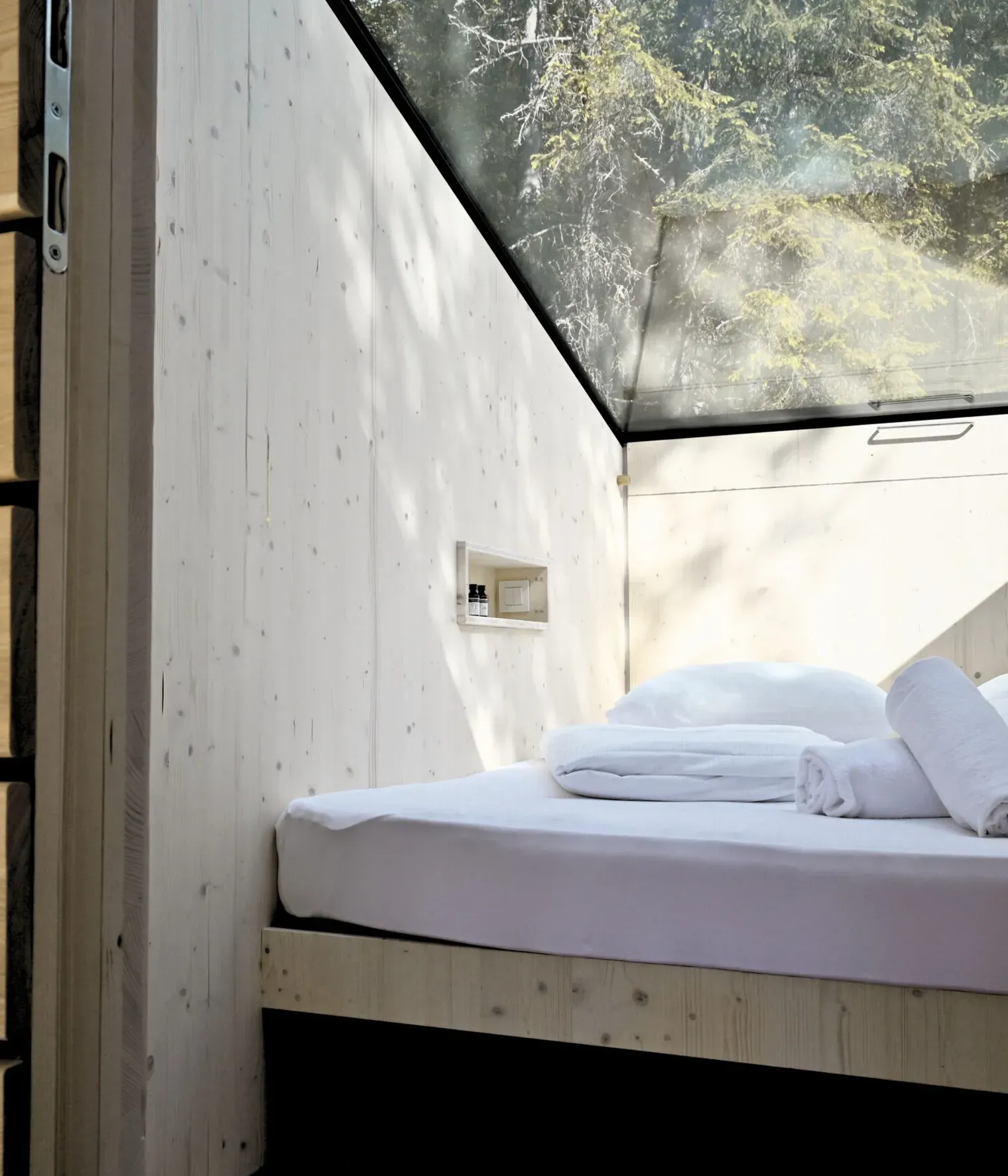 Interno della Stargazing Cabin con letto matrimoniale e tetto vetrato affacciato sul bosco